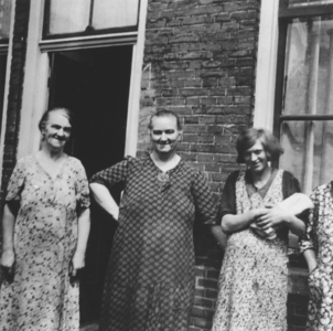 876892 Groepsportret van drie onbekende vrouwen staande voor de woning met het nr. 1 op een onbekende straat in Wijk C ...